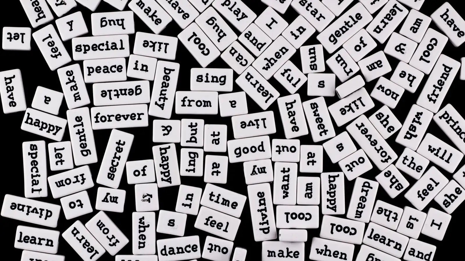 A collection of scattered word tiles on a black surface, creating a chaotic word jumble.